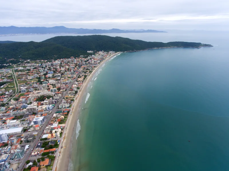 Vista aérea da orla de Bombas, com faixa de areia e ocupação urbana. Acervo de 2018.